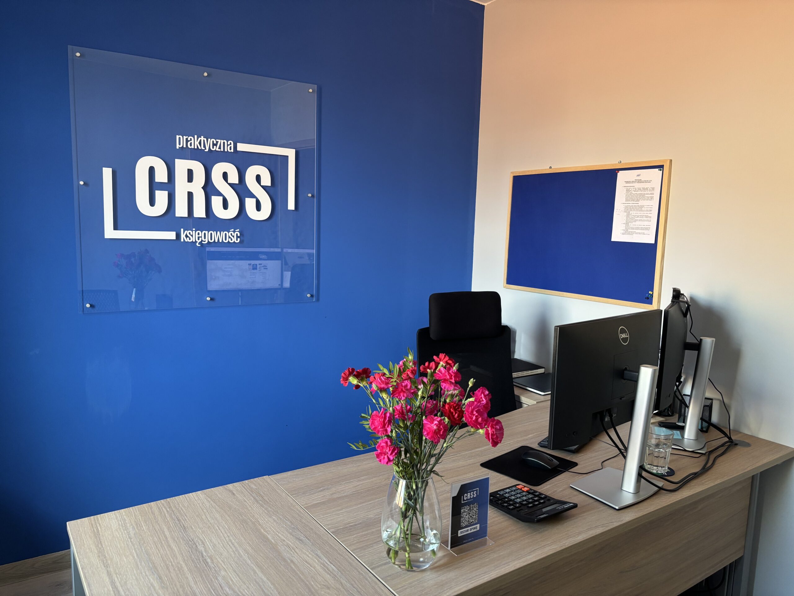 Księgowa doradza właścicielowi małej firmy przy biurku z laptopem, kalkulatorem i uporządkowanymi dokumentami — usługi księgowe, podatki, kadry i wsparcie przy pozyskiwaniu dotacji.